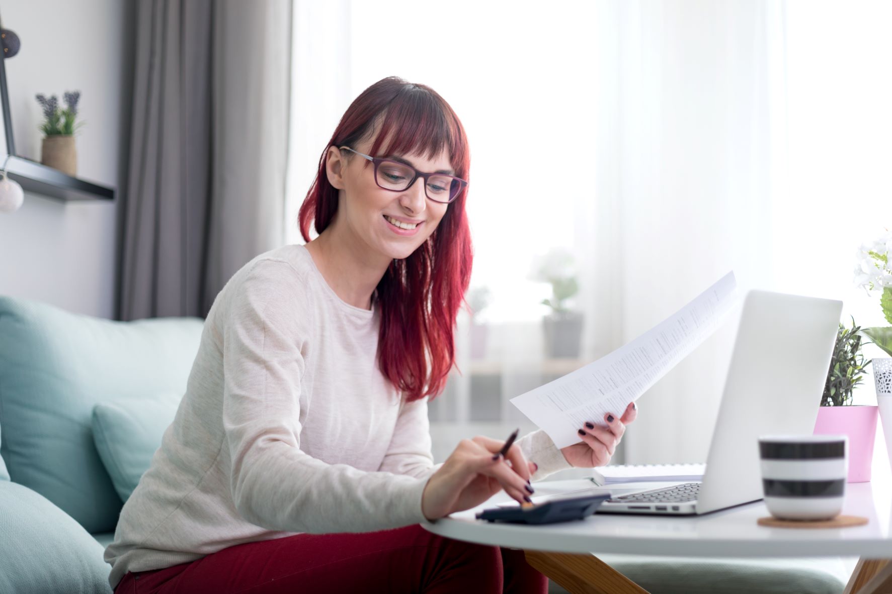 happy woman at home using a laptop and checking bills