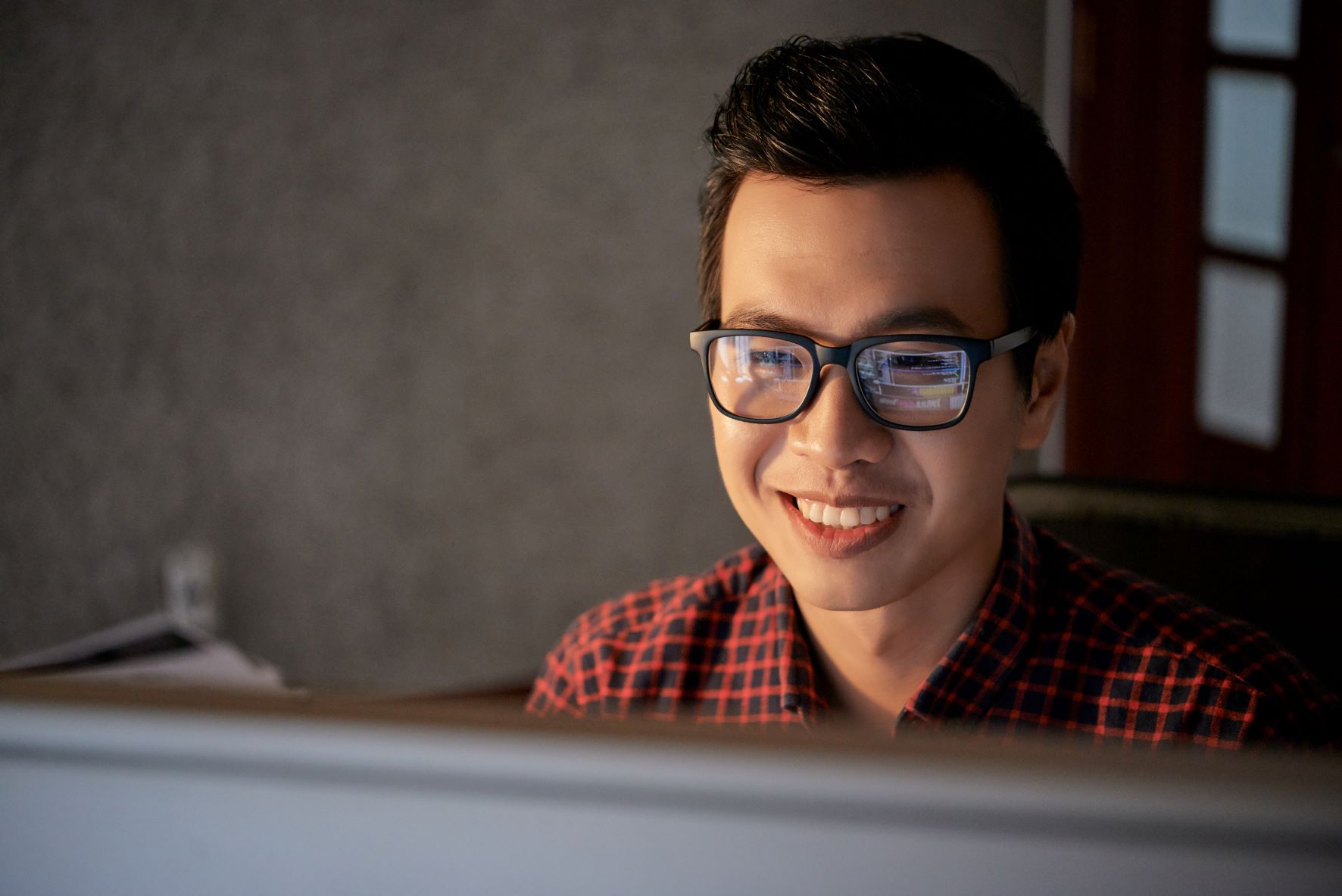 asian man with glasses looking at computer screen